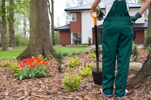 Gardener performing routine garden maintenance with tools and protective gear