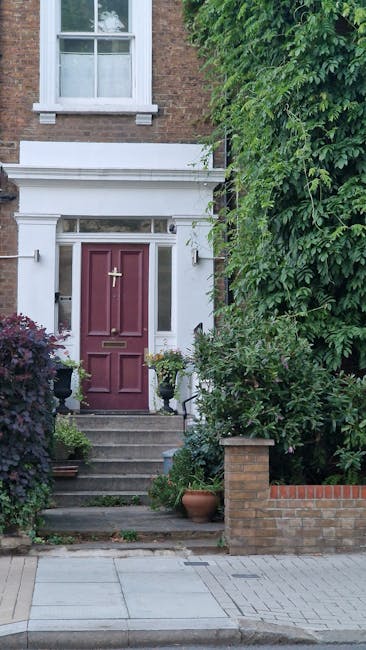 A close-up view of a front garden entrance in Penge, featuring a deep red wooden door with a brass letterbox and decorative latch, set within a white painted frame with classic architectural detailing